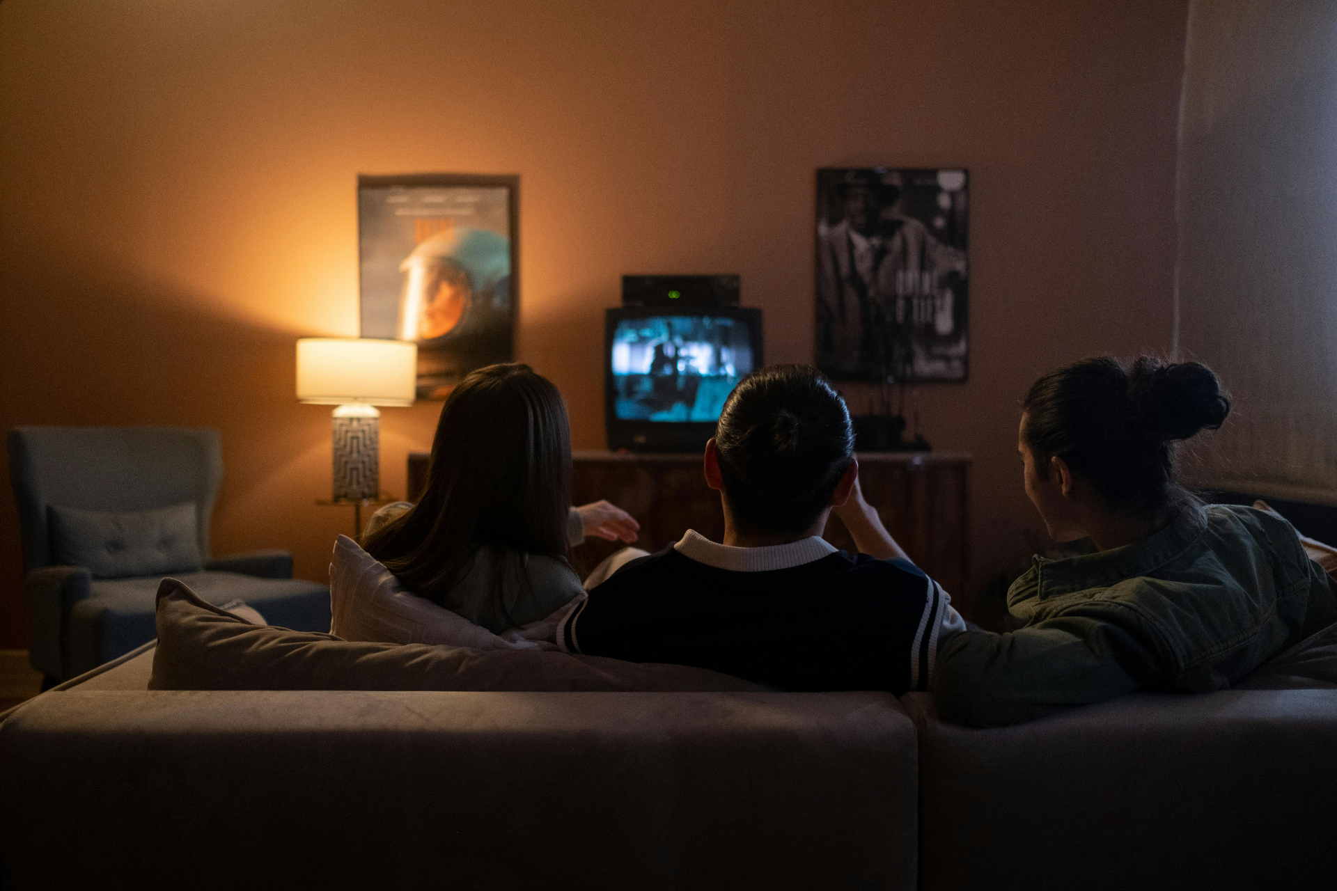 Friends watching television together in a warmly lit living room